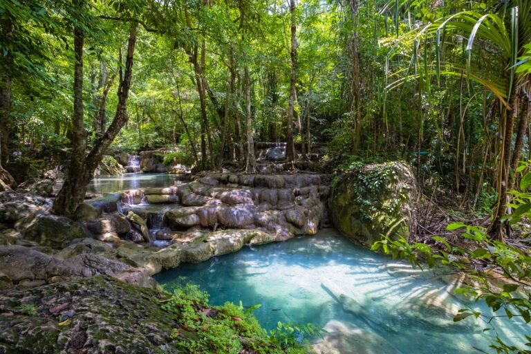 Explore the serene beauty of a lush Thai rainforest with stunning waterfalls cascading into tranquil pools.