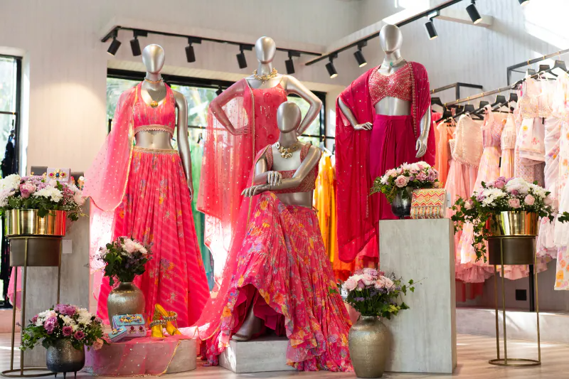 Olivia Clothing Store showcasing vibrant pink and red Indian ethnic wear, lehengas, sarees, and festive outfits on mannequins.