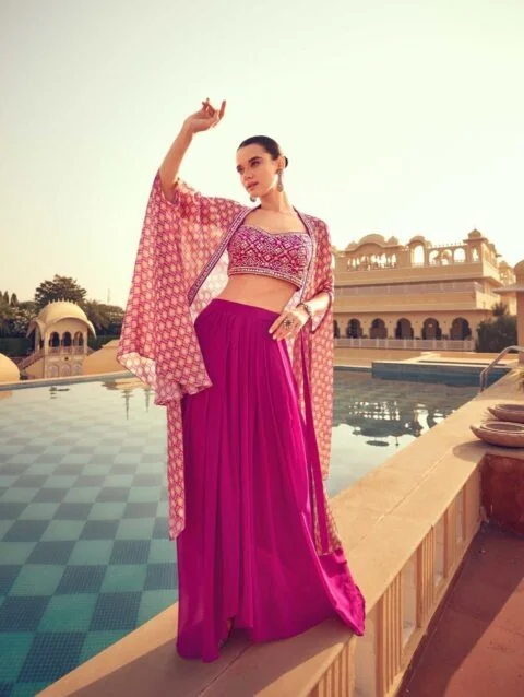 Olivia Clothing Store women's ethnic fashion collection featuring a model wearing a stylish pink lehenga, embroidered blouse, and designer shrug, showcasing elegant festive and wedding wear in a luxurious outdoor setting